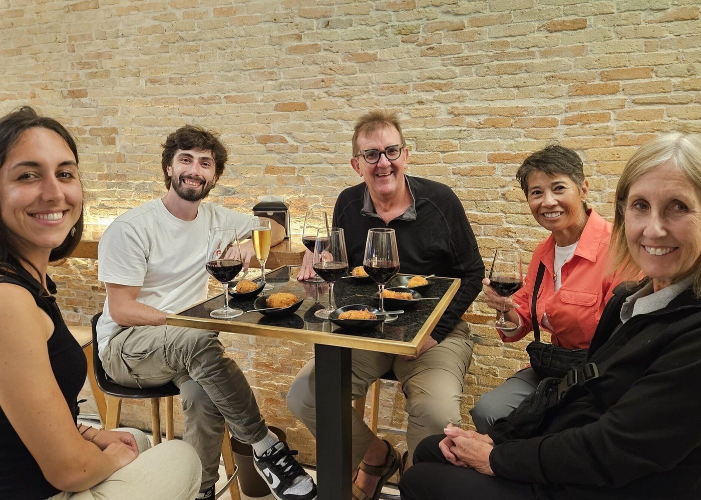 A group of five holding wine glasses at a pintxo bar table