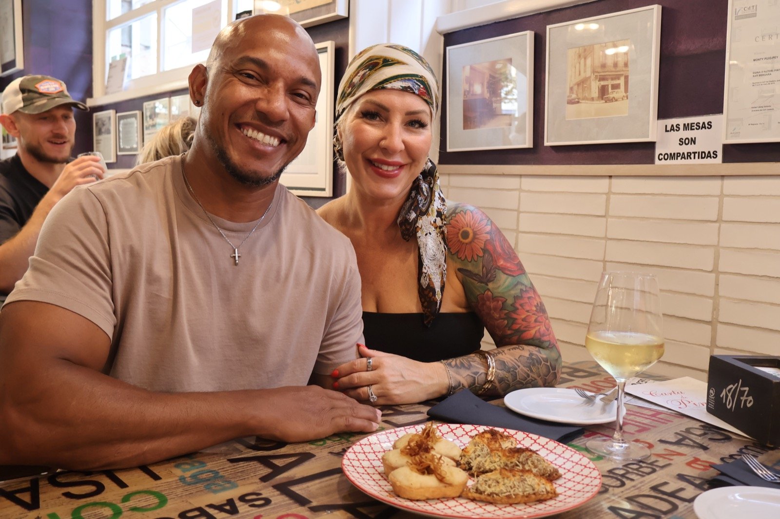 A couple sharing a plate of pintxos at a bar with communal tables
